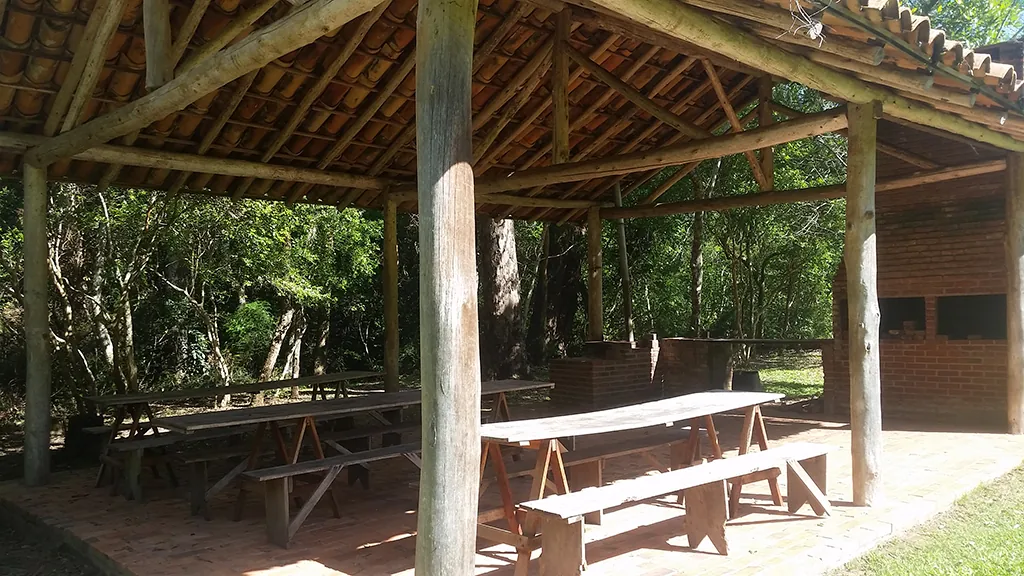 Interior de quiosque do Eco Parque com mesas e bancos